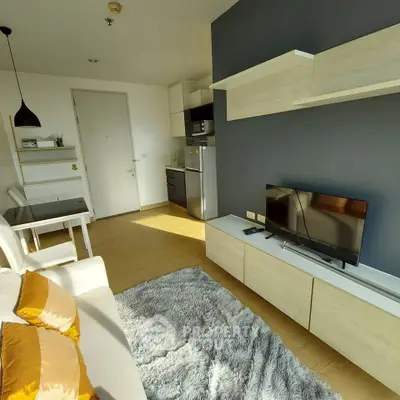 Modern living room with stylish furniture and natural light, featuring a cozy rug and sleek TV setup.