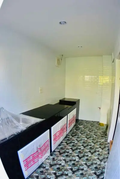 Compact kitchen with black countertops and tiled flooring in a modern apartment.