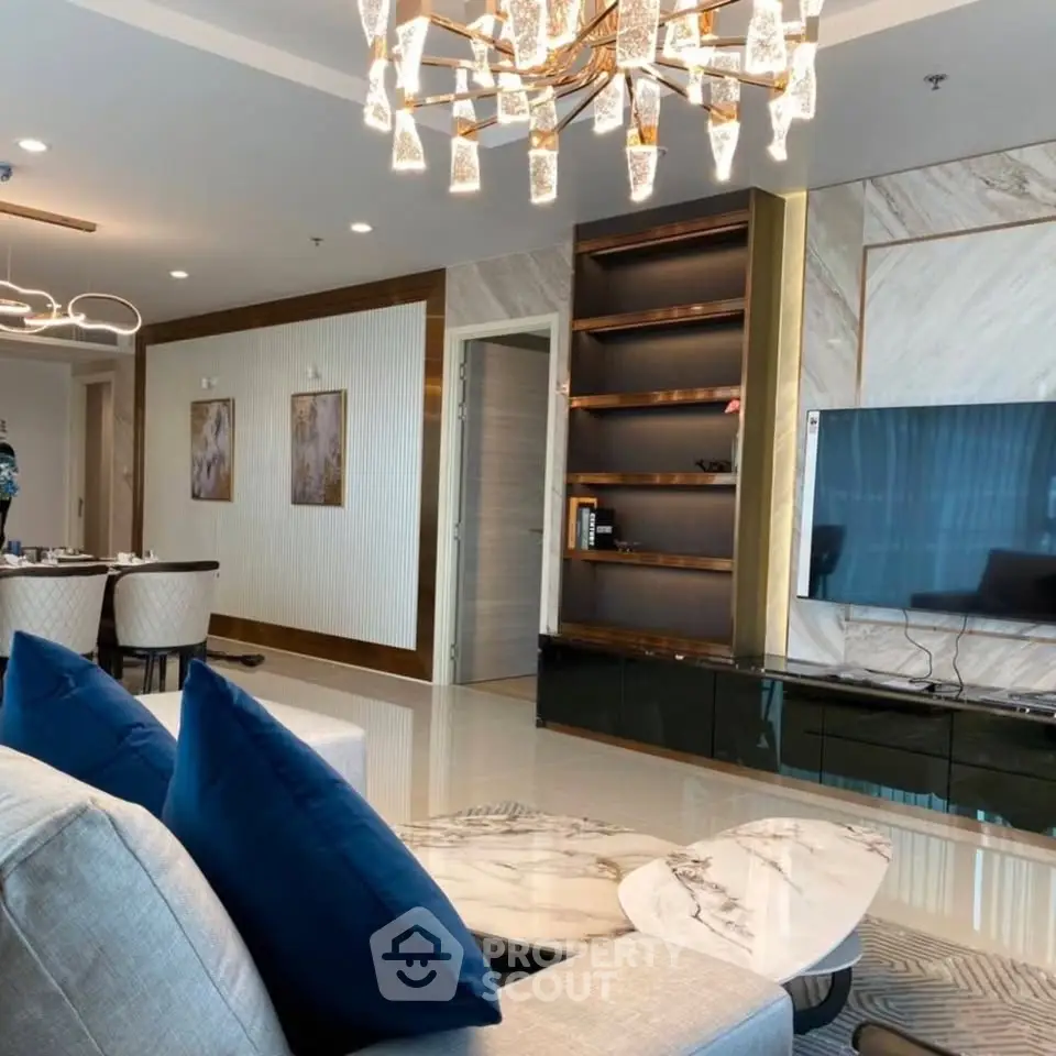 Luxurious living room with modern decor, elegant chandelier, and sleek TV setup.