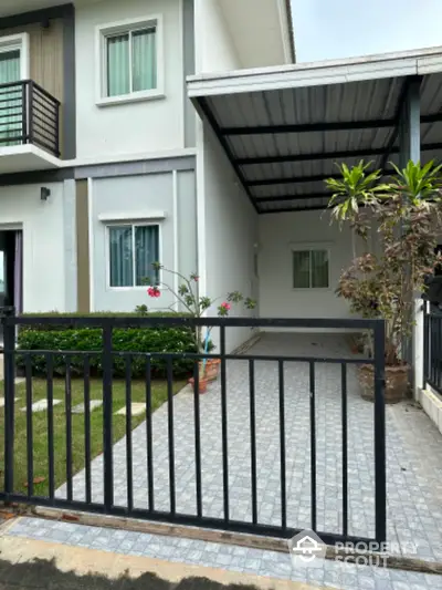 Modern townhouse with gated driveway and lush greenery in a serene neighborhood.