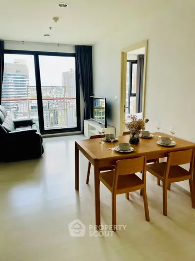 Modern living room with dining area and city view, featuring sleek furniture and large windows.