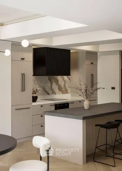 Modern kitchen with sleek design, featuring marble backsplash and stylish island seating.