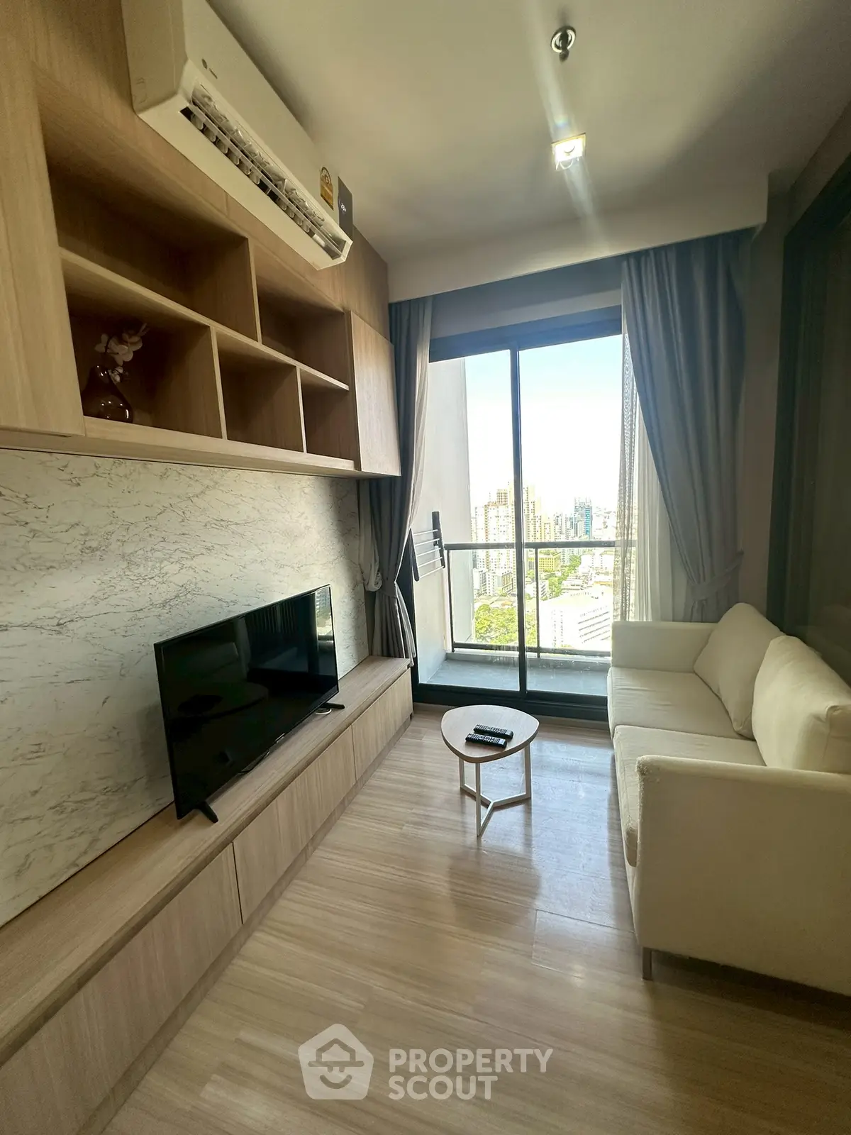 Modern living room with balcony view, featuring sleek wooden furniture and a cozy white sofa.