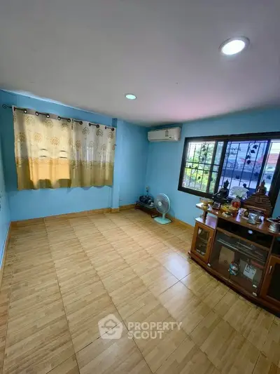 Spacious living room with wooden flooring and large window offering natural light.