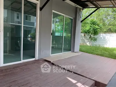 Spacious outdoor patio with sliding glass doors and lush greenery, perfect for relaxation and entertainment.