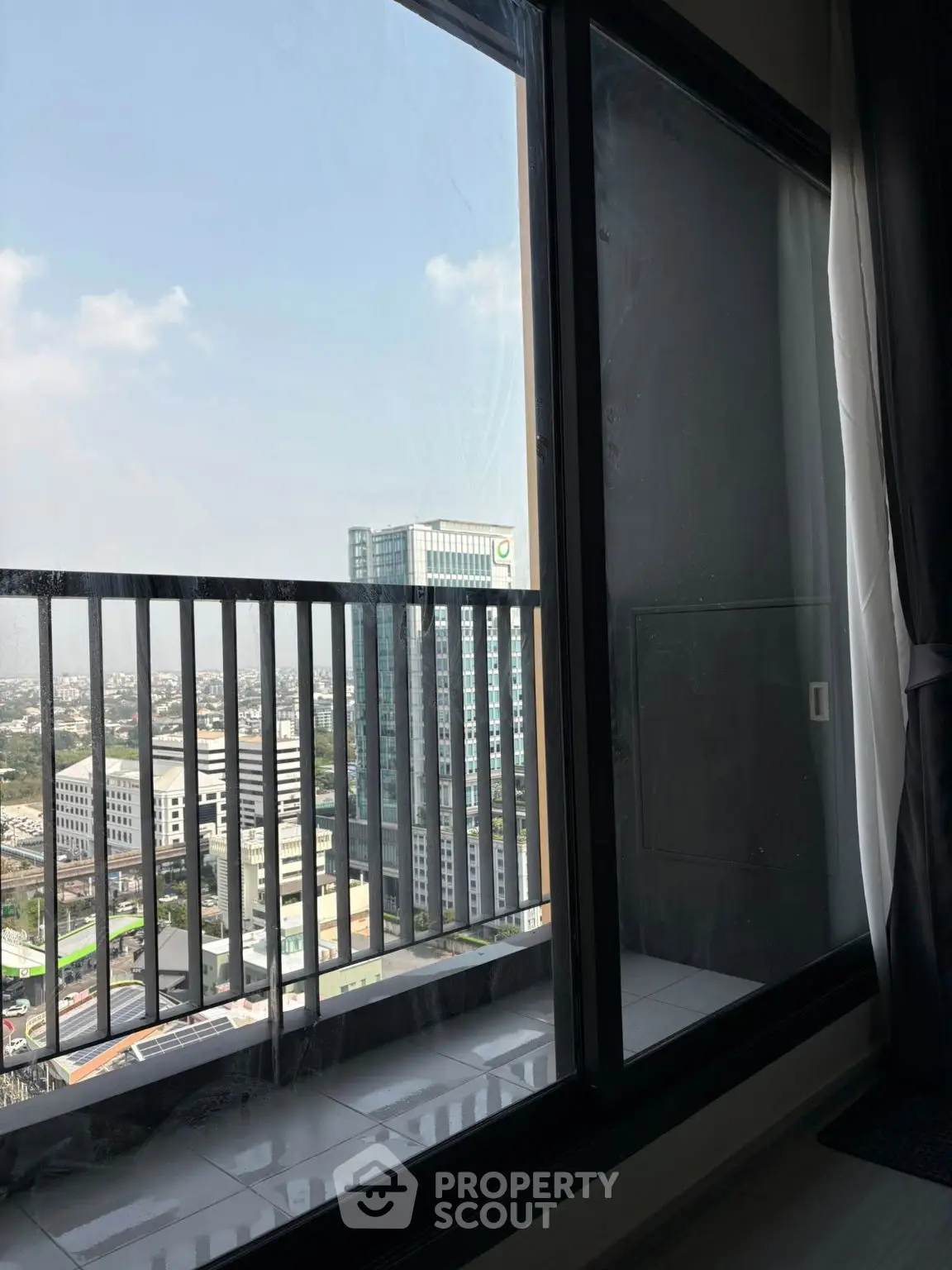 Stunning city view from high-rise apartment balcony with glass railing.