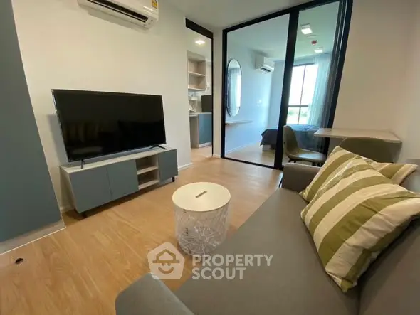 Modern living room with TV, stylish furniture, and a glimpse into a cozy bedroom.