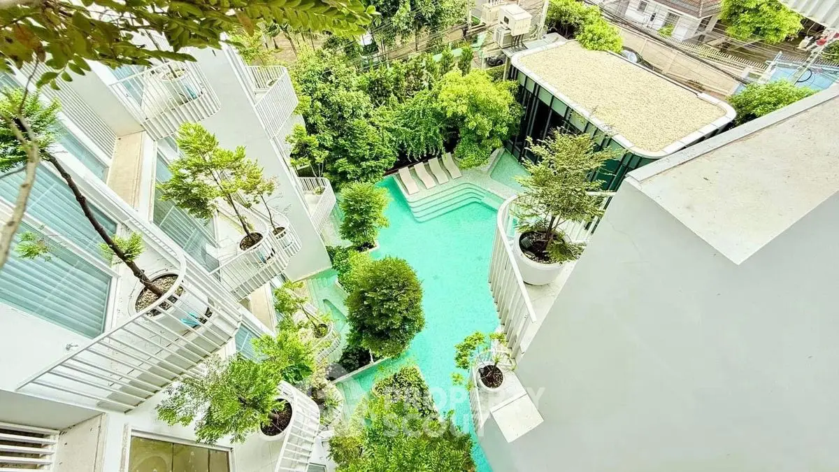 Stunning aerial view of modern building with lush greenery and inviting pool area.