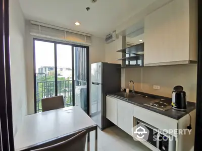 Modern kitchen with sleek cabinetry and built-in appliances, opening onto a cozy balcony with natural light.