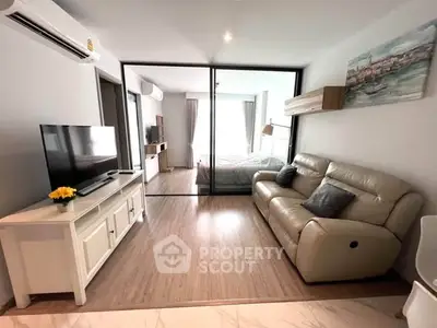 Modern living room with sleek design and cozy seating, featuring a view into a stylish bedroom.