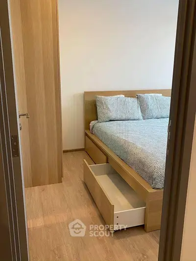 Cozy bedroom with wooden flooring and modern bed featuring storage drawers.