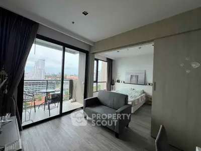 Modern studio apartment with balcony and city view, featuring sleek furniture and open layout.