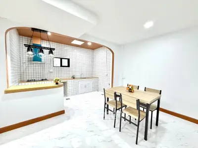 Modern kitchen with open layout and dining area, featuring sleek design and bright lighting.