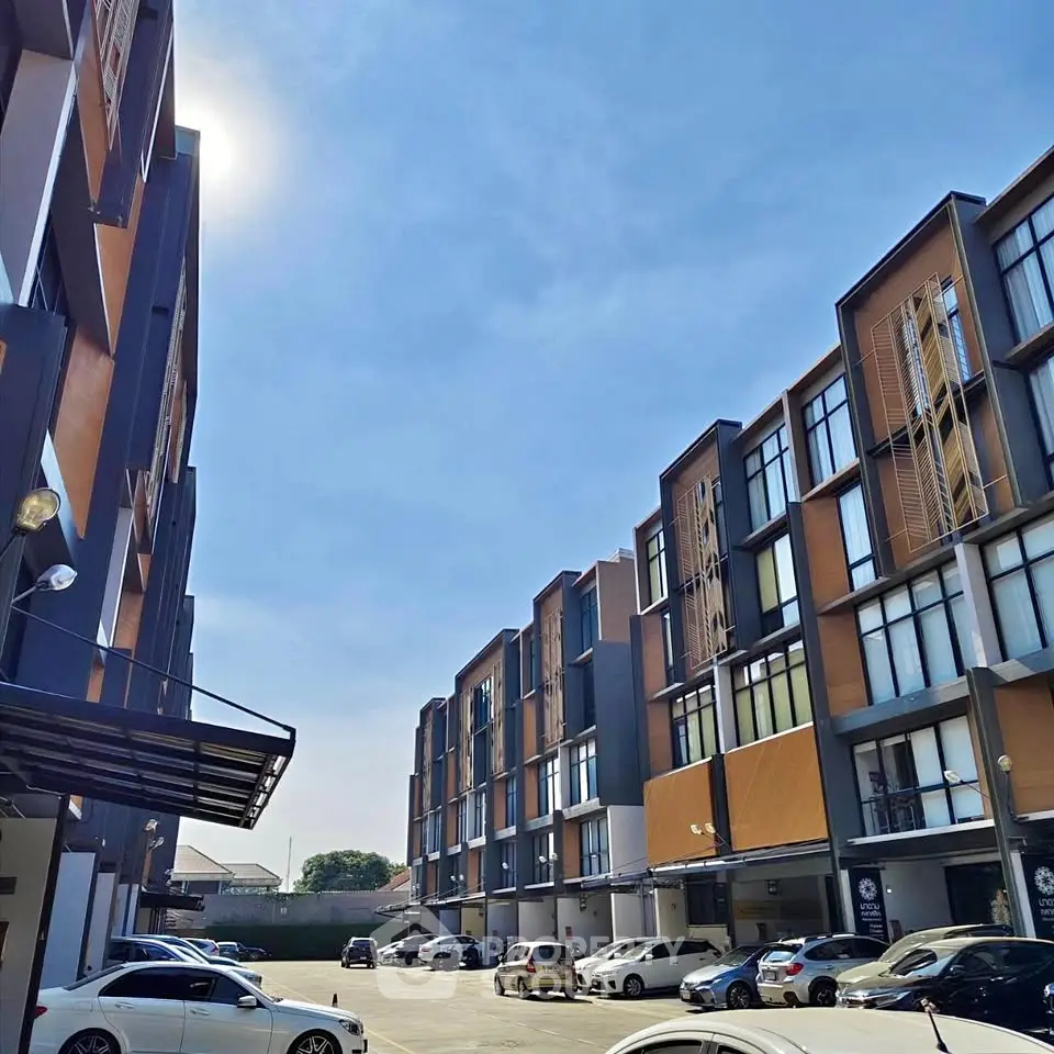 Modern townhouse complex with ample parking and clear blue sky.