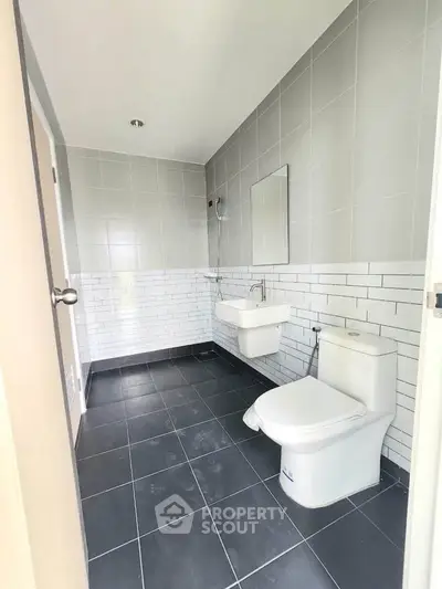 Modern bathroom with sleek gray tiles and white fixtures in a contemporary home.
