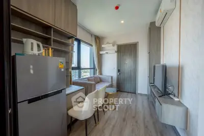 Modern living room with sleek furniture and city view, featuring a compact kitchen area and stylish decor.