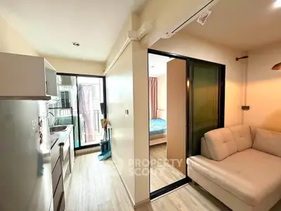 Modern apartment interior with cozy living room and compact kitchen, featuring sliding doors to a bedroom.