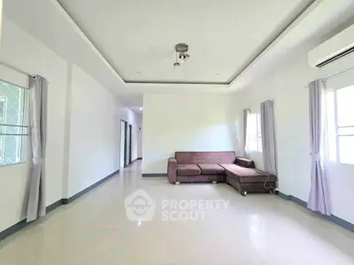 Spacious living room with modern sofa and natural light, perfect for relaxation and entertaining.