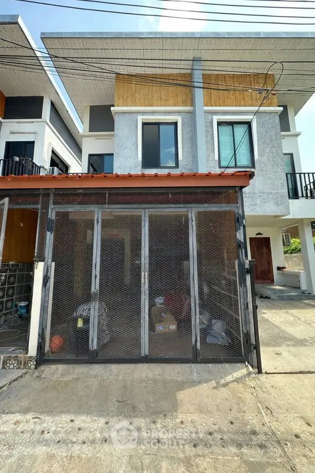 Modern two-story house with gated entrance and contemporary design in a suburban neighborhood.