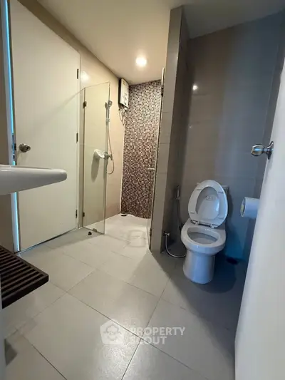 Modern bathroom with glass shower and sleek fixtures in contemporary apartment.