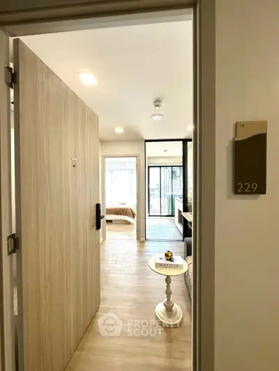 Modern apartment entrance with open door leading to a bright bedroom and stylish interior.