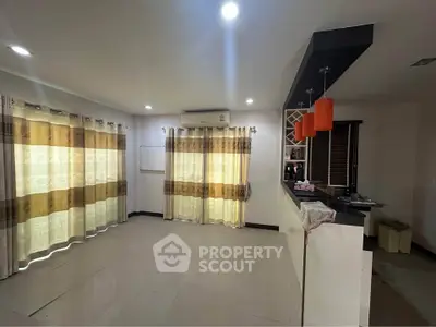 Spacious living room with open kitchen and modern lighting in a cozy apartment.