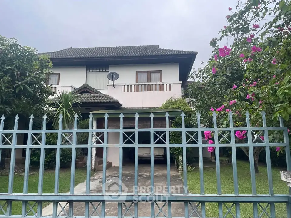 Charming two-story house with lush garden and gated driveway, perfect for family living.