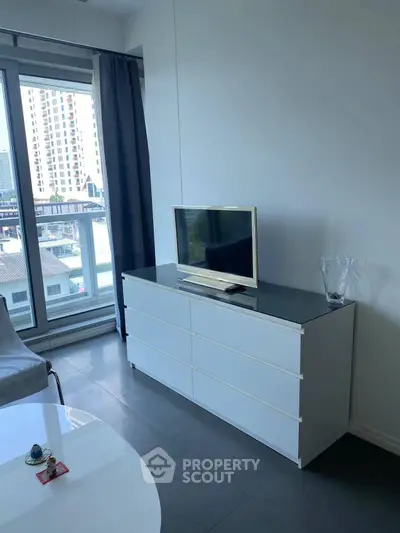 Modern living room with sleek white dresser and city view from large window.