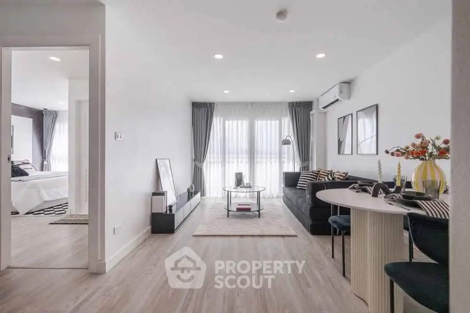 Modern living room with stylish decor and open layout leading to a cozy bedroom.