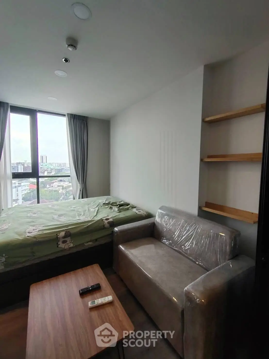 Modern studio apartment with cozy living area and large window view.