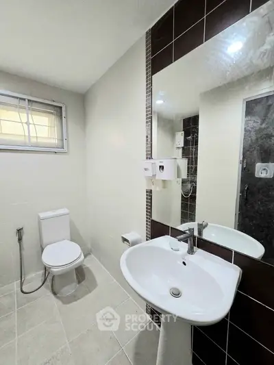 Modern bathroom with sleek fixtures and neutral tiles, featuring a large mirror and natural light.