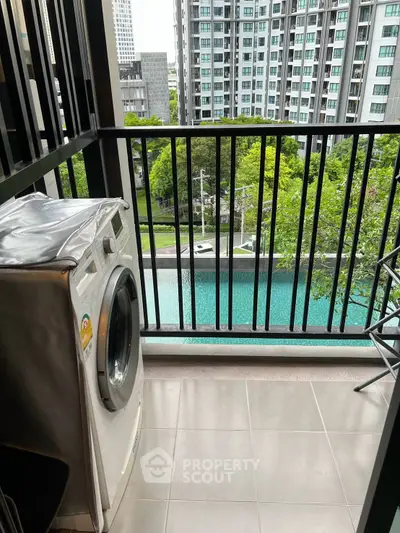 Modern balcony with washing machine overlooking pool and cityscape view.