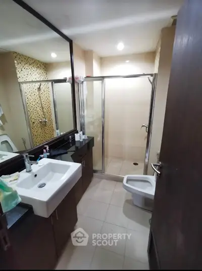 Modern bathroom with glass shower and sleek vanity in contemporary apartment.