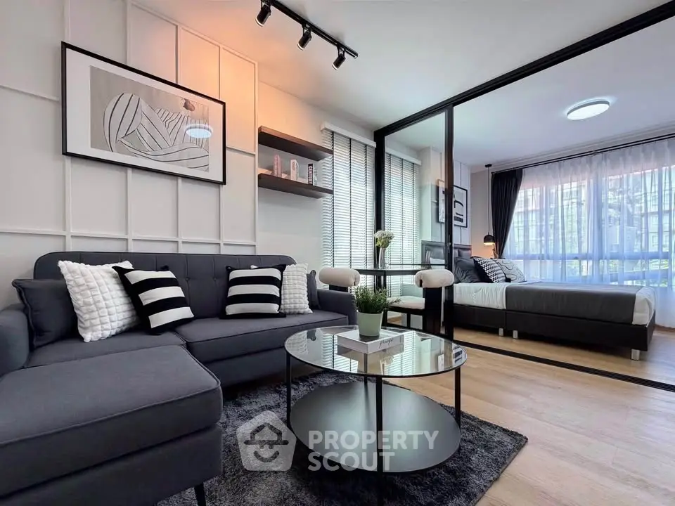 Modern open-plan living room with stylish decor and cozy bedroom area