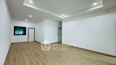 Spacious empty room with wooden flooring and recessed lighting, ideal for customization.