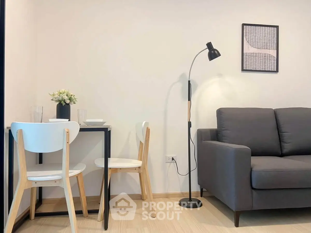 Modern living room with cozy sofa, stylish floor lamp, and compact dining area for two.
