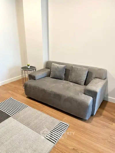 Modern living room with stylish gray sofa and chic side table on wooden flooring.