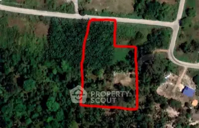 Aerial view of a lush green plot of land outlined in red, ideal for development or agriculture.