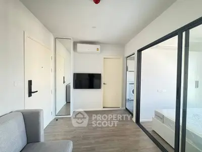 Modern apartment interior with sleek design, featuring a cozy living area and a glimpse of the bedroom.