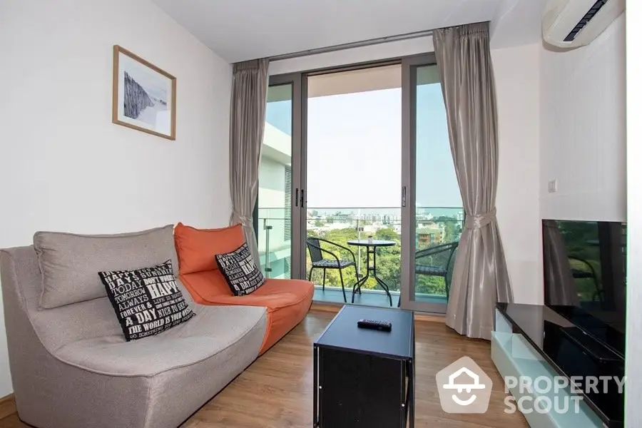 Modern living room with balcony view, stylish furniture, and natural light.