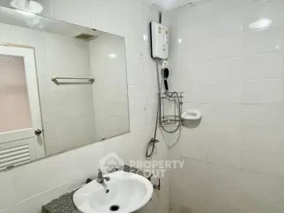 Compact bathroom with white tiles and modern sink in real estate property.