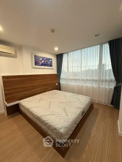 Spacious bedroom with modern decor and large window offering natural light.