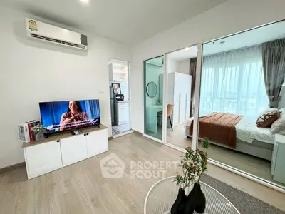 Modern living room with TV and view into cozy bedroom through glass doors.