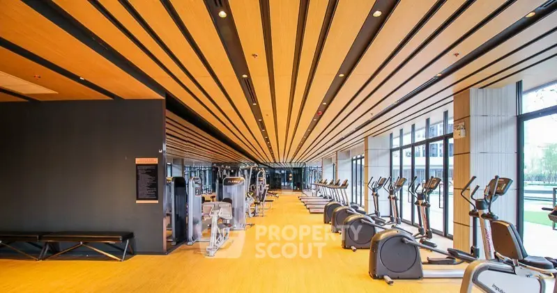 Spacious modern gym with state-of-the-art equipment and large windows for natural light.