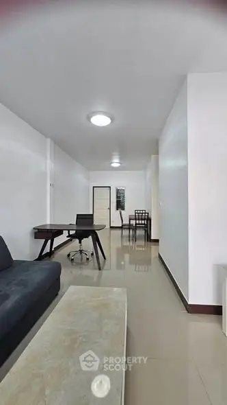 Spacious modern living room with sleek furniture and glossy tiled floors in a contemporary apartment.