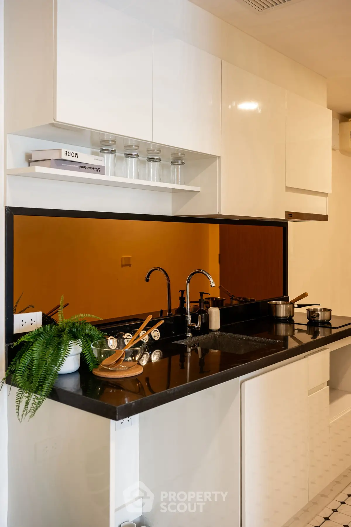 Modern kitchen with sleek black countertop and white cabinets, featuring a stylish open layout and contemporary fixtures.