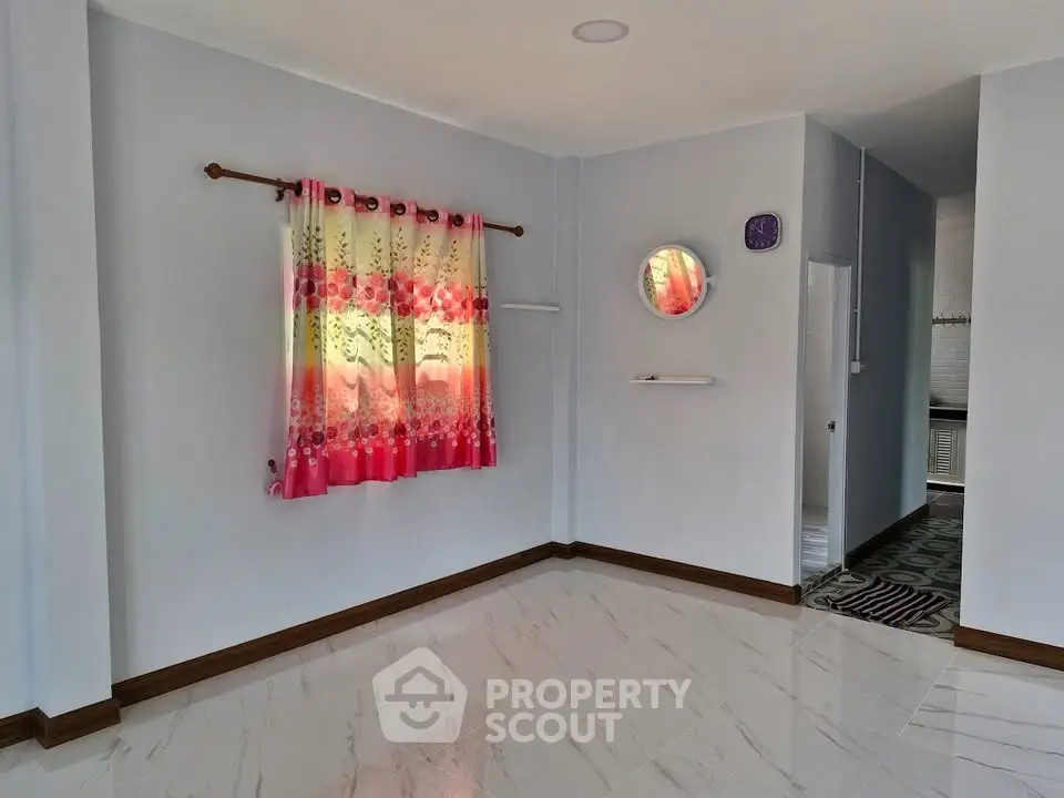 Spacious empty room with elegant tile flooring and vibrant curtains, perfect for customization.