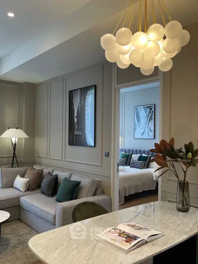 Luxurious open-plan living room with elegant decor and view into a stylish bedroom, featuring modern lighting.