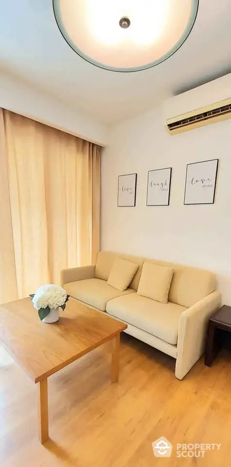 Cozy living room with beige sofa, wooden coffee table, and wall art in modern apartment.