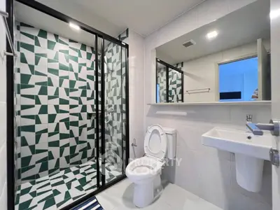 Modern bathroom with geometric tile shower and sleek fixtures.